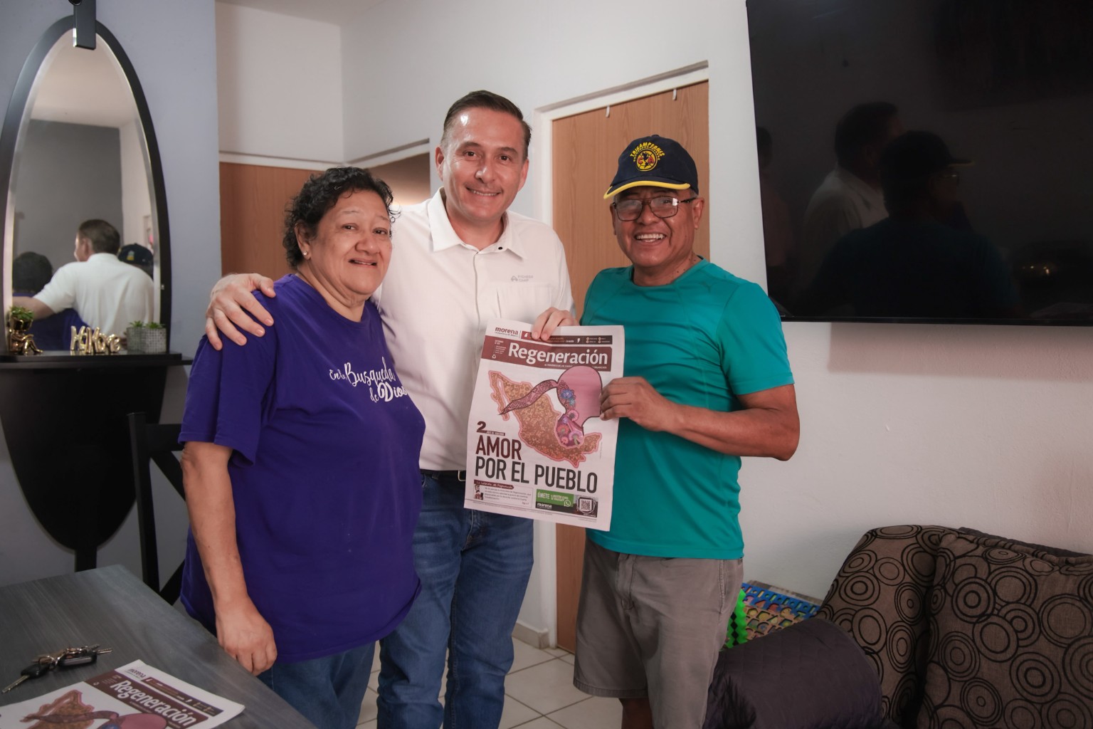 Jehú Kiko Vázquez posa con dos personas que muestran el periódico Regeneración.